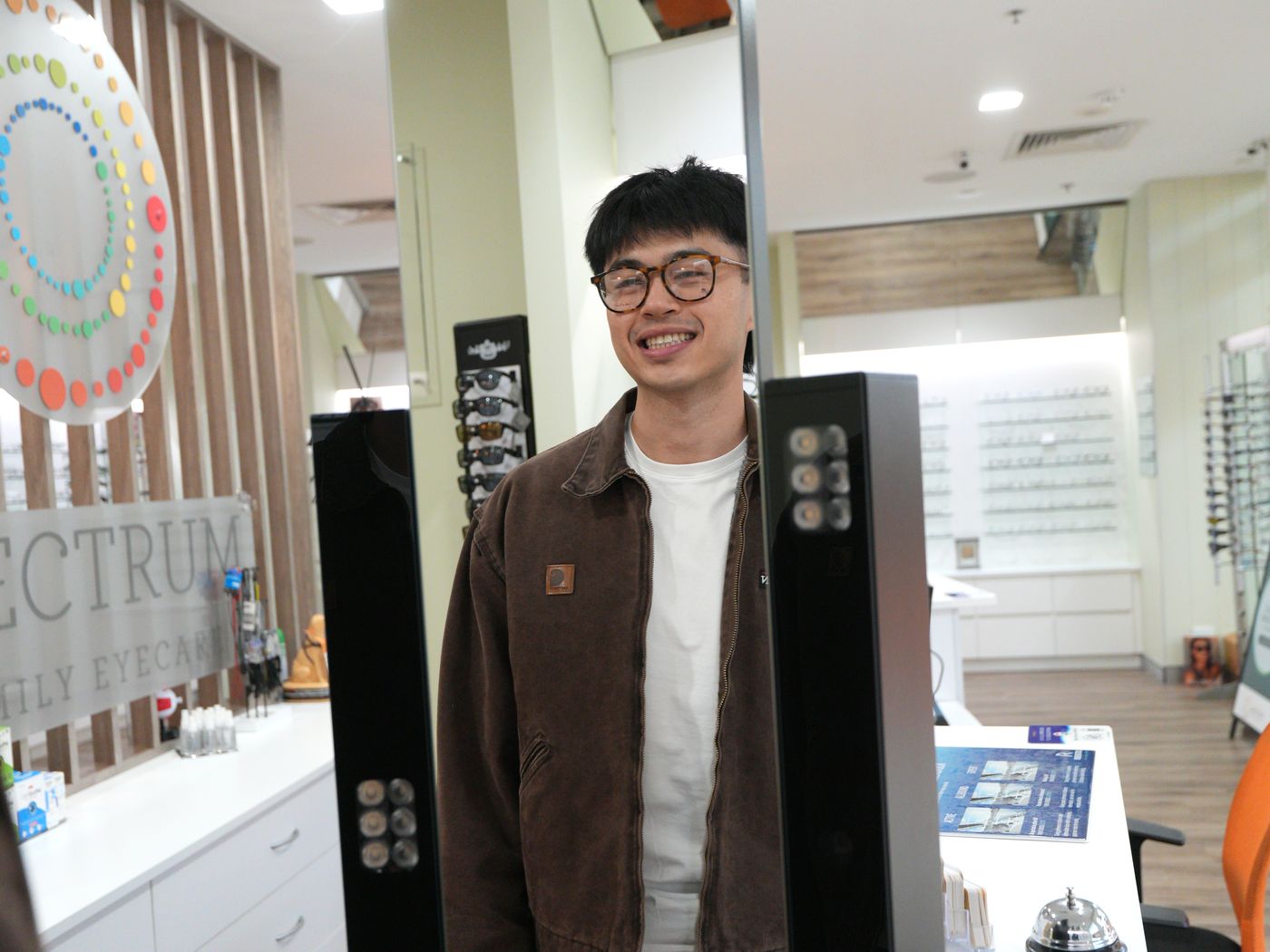 A young patient trying on frames in front of the mirror at Spectrum