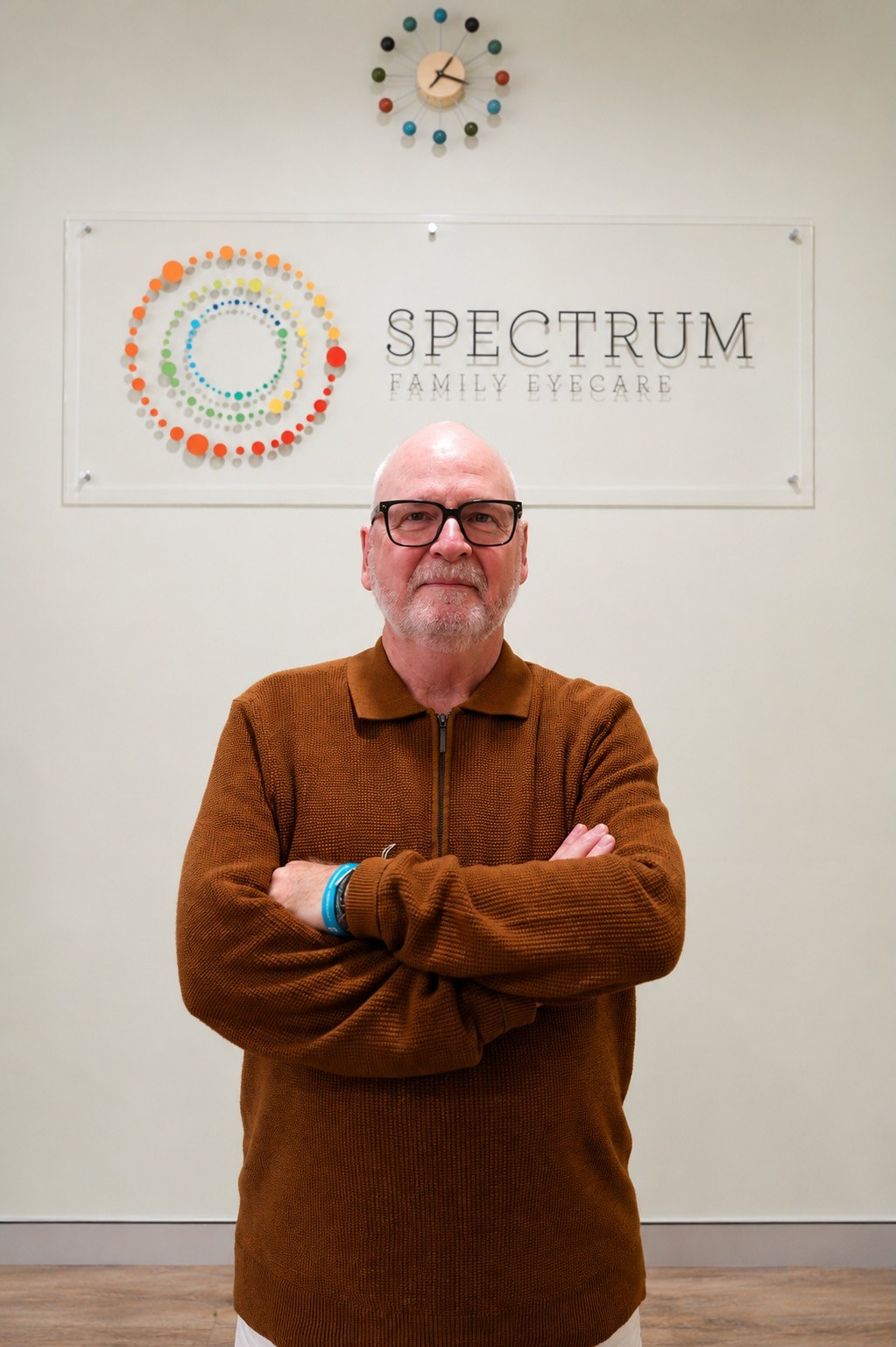 Paul, colorimetry and visual stress specialist, standing in front of the Spectrum Family Eyecare signage wall.