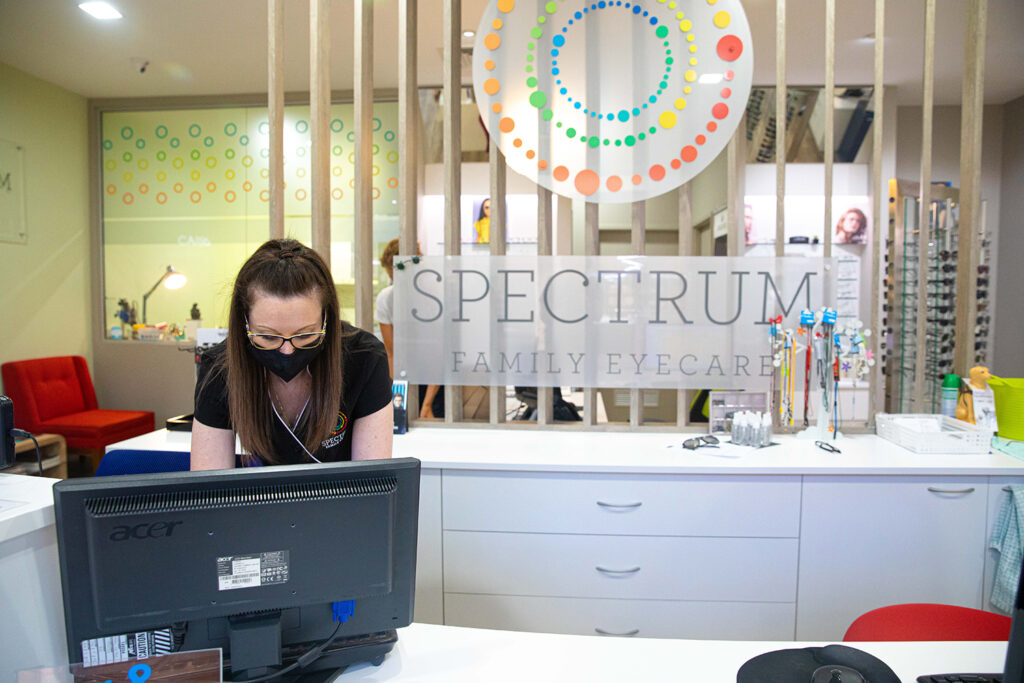 The warm, welcoming reception desk of Spectrum Family Eyecare where an employee is working